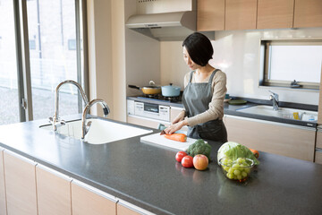 Woman cooking standing in beautiful kitchen with copy space to the right