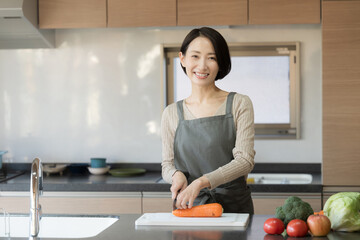 綺麗なキッチンに立つ料理をする女性　左にコピースペースあり