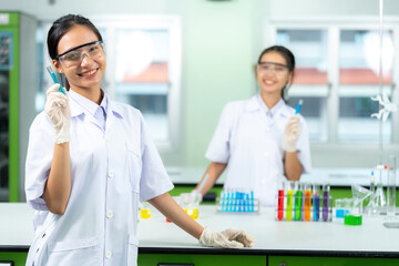 Two Asian female scientists are students. holding a test tube with chemical water in the lab On the...