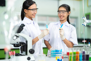 Two Asian female scientists look like college students. Experiment with chemicals in the lab There...