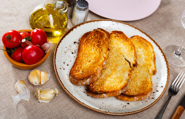 Crispy toasted white bread slices, fresh ripe tomatoes and garlic served on plates. Ingredients for...
