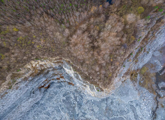Stone quarry in the forest. Flying over the autumn mixed forest during sunset. The surroundings of Yekaterinburg. Ural, Russia, Aerial View