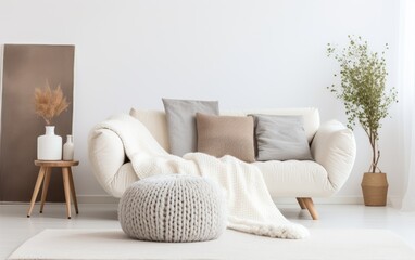 Scandinavian home interior design of modern living room. Knitted pouf, fabric sofa with blanket and pillows