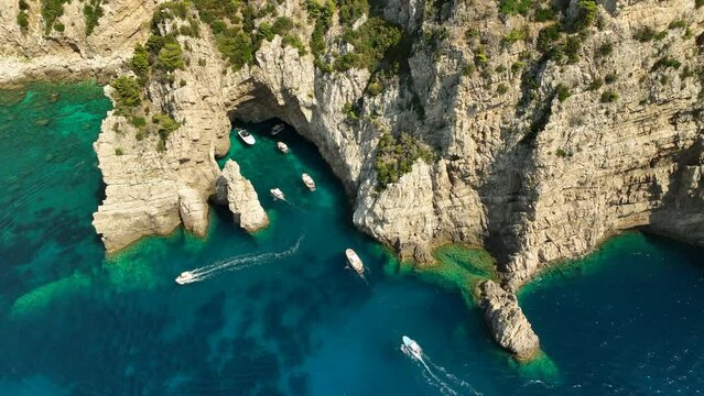 Tourists sailing into Grotta Verde on the Italian island Capri on a sunny day. Drone dolley tilt shot