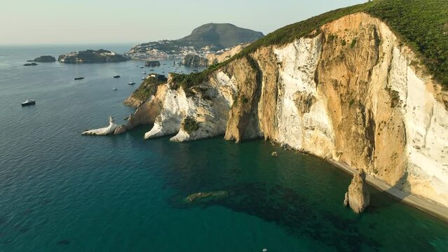 Large tuff and kaolin rock formation with Ponza Bay in the background. Drone dolly shot