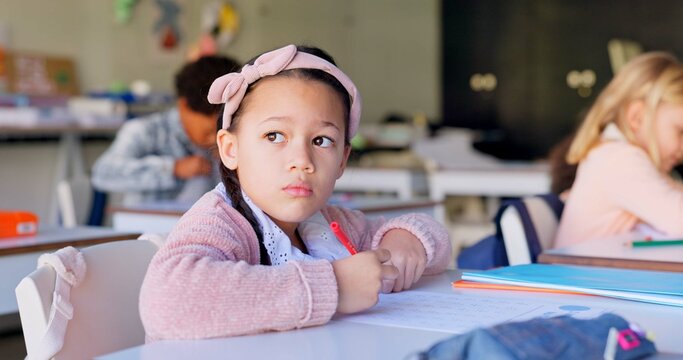 Child, thinking and pen with paper by desk, education and solving a mathematics problem with question. Young student, confused and solution to assessment in classroom, elementary school and academy