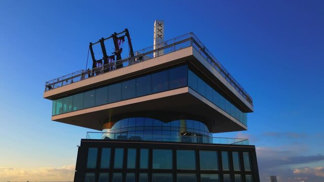 Swinging at Adam observation deck rooftop at sunset in Dutch capital