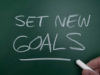 Set new goals, text written on chalkboard, life and business quote