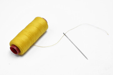 Yellow thread and needle over white
