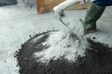 Worker using hoe to mixing sand and cement manually at construction site - obrazy, fototapety, plakaty
