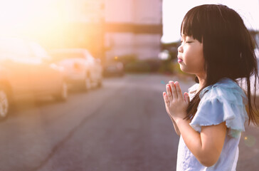 Little asian girl hand praying in morning sunrise light.