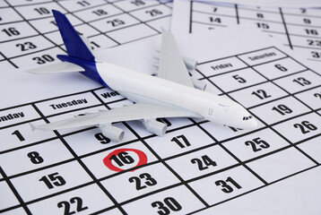 Airplane model on calendar page with marked day. Planning vacation concept. 