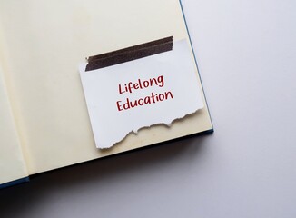 Book with stick note written Lifelong Education, means education resulting from integration of...