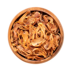 Dried mace in a wooden bowl. Spice with pale yellow and orange tan, made of seed coverings of...