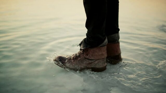 Man with leather boots walking into shallows of Dead Sea. Slow motion, close-up