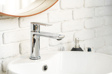 Bathroom interior with circle shaped mirror in wooden frame and white sink