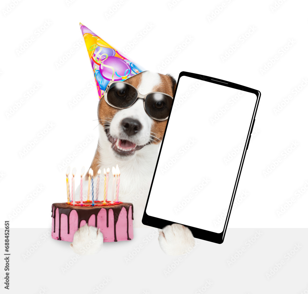 Poster jack russell terrier puppy wearing sunglasses and party cap holds cake with lots burning candles and