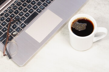 コーヒーを飲みながらノートパソコンでデスクワークをしているイメージ
