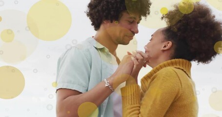 Animation of light spots over happy biracial couple dancing on beach - Powered by Adobe