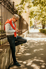 Fototapeta premium A senior man leisurely strolls through the city, phone in hand, capturing the essence of urban exploration