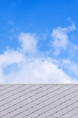 Roof tiles against clouds in the blue sky. - 688461230