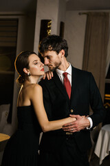 A stylish man and woman in evening wear, a suit and a dress, posing against the backdrop of a luxurious hotel. Casino concept