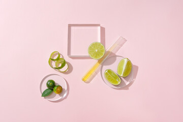 Glass platform, a petri dish, a test tube, fresh lemons and kumquats stand out on a light pink background. Space for displaying natural cosmetics with lemon extract.