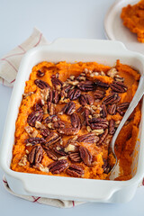 Traditional sweet potato casserole with pecan, white background.