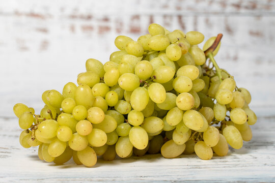 Fresh green grapes on a white wooden background. Organic agricultural products. Delicious bunch of grapes