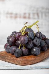 Fresh black grapes on a white wooden background. Organic agricultural products. Delicious bunch of grapes