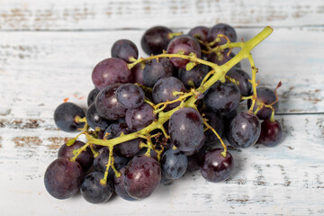 Fresh black grapes on a white wooden background. Organic agricultural products. Delicious bunch of grapes