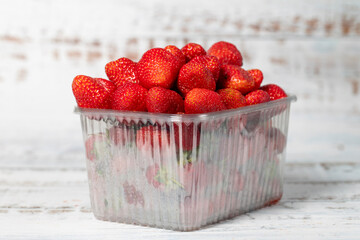 Packaged strawberries on a white wooden background. Organic agricultural products. Delicious ripe...