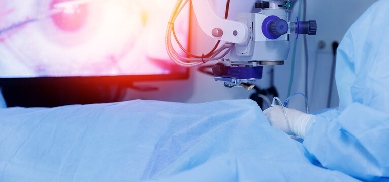 Lasik treatment. Laser vision correction. Doctor examines fundus in microscope, patient under sterile cover.