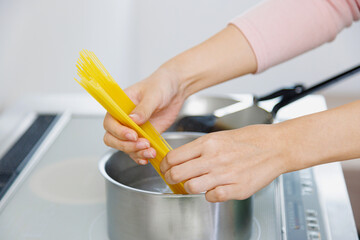 キッチンでスパゲッティを調理する女性