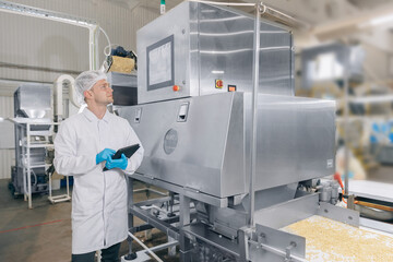 Concept modern food industry, factory production line. Worker man control quality product on automatic conveyor belt for transporting cedar nuts