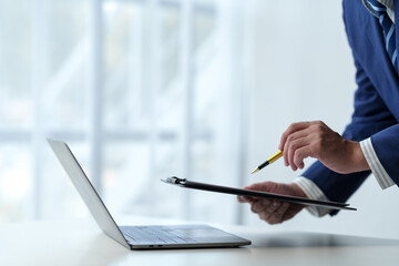Businessman working on laptop, checking email, sending information online on desk Holding a work...