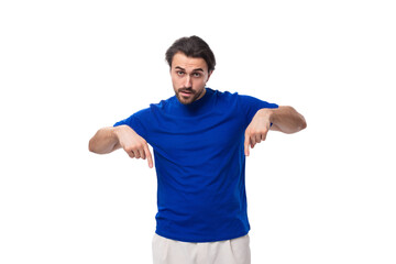 a young brutal European brunette man with a beard dressed in a blue T-shirt gesticulates with his...