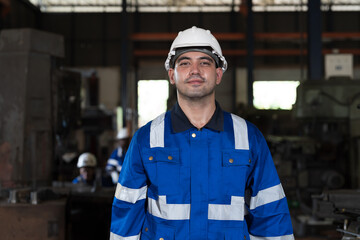 Portrait of male engineer worker working in factory, wearing safety uniform, helmet while holding equipment tools