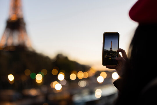 tourist woman takes photo of the eiffel tower at sunset