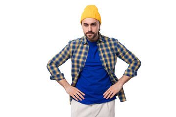 well-groomed authentic young european brunette man with a brutal beard and mustache dressed in a yellow hat and blue shirt