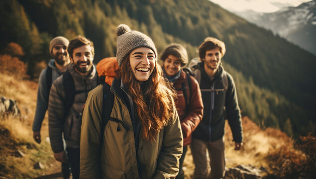 A group of young adults of various nationalities in hiking attire, with backpacks, smiling and walking in a mountainous area.