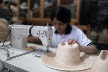 A young Hispanic woman is sewing a natural fiber hat