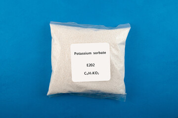 Potassium sorbate in transparent plastic bag on blue background. Food additive E202. Chemical...