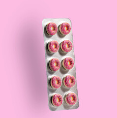 Pill blister with pink donuts instead of pills on  pink background. Sugar addiction concept.