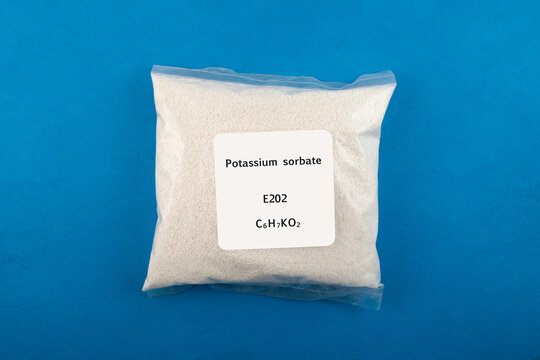 Potassium sorbate in transparent plastic bag on blue background. Food additive E202. Chemical formula C6H7KO2. Potassium sorbate, oblong pellets. Granular potassium salt of sorbic acid