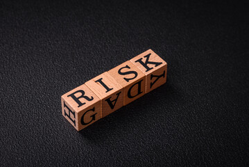 The inscription risk with wooden cubes on a dark concrete background