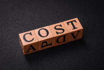 The inscription cost in wooden cubes on a dark concrete background