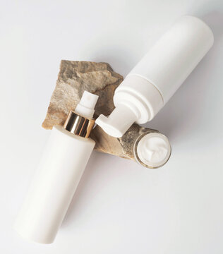 Cosmetic products in white bottles on the stone. Open jar of moisturizer. Top view. Natural cosmetics concept