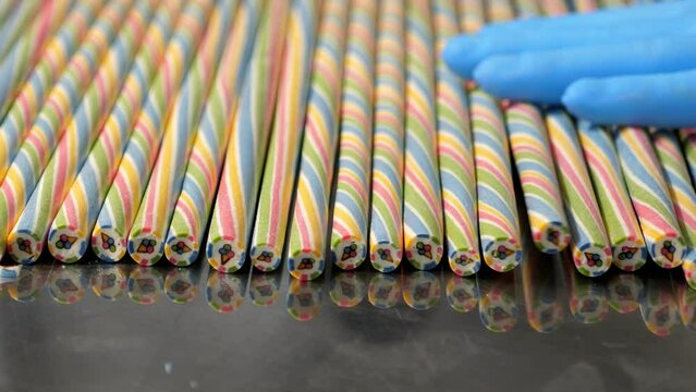 Close-up of striped long caramel candies with a pattern inside on a metal table in a pastry shop. The process of making handmade craft lollipops.
