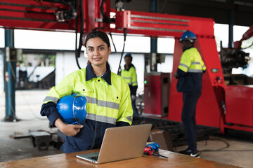 Female engineer inspecting quality and maintenance autonomous robotics arm system welding in factory